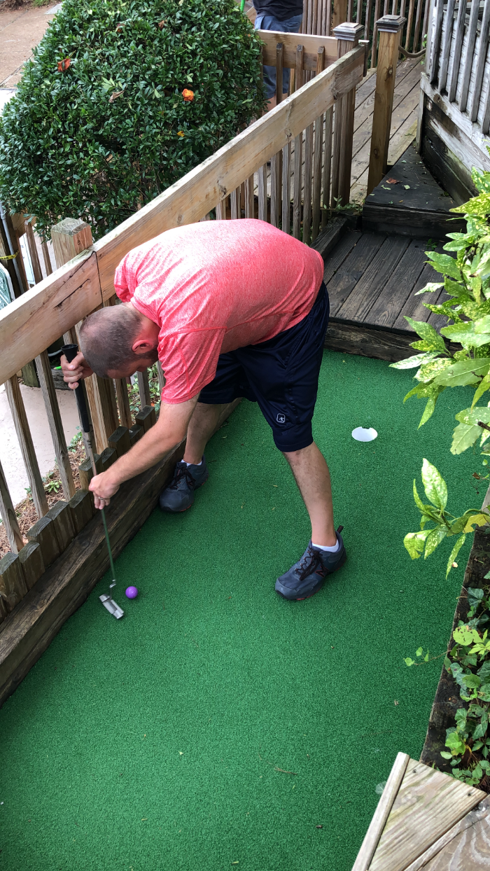 A player bent over a putt against the rail